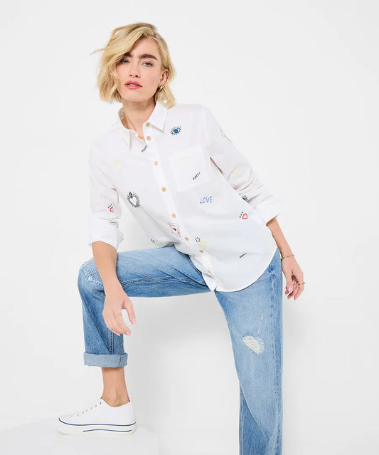 Woman wearing a white shirt with colorful designs and blue jeans on a white background