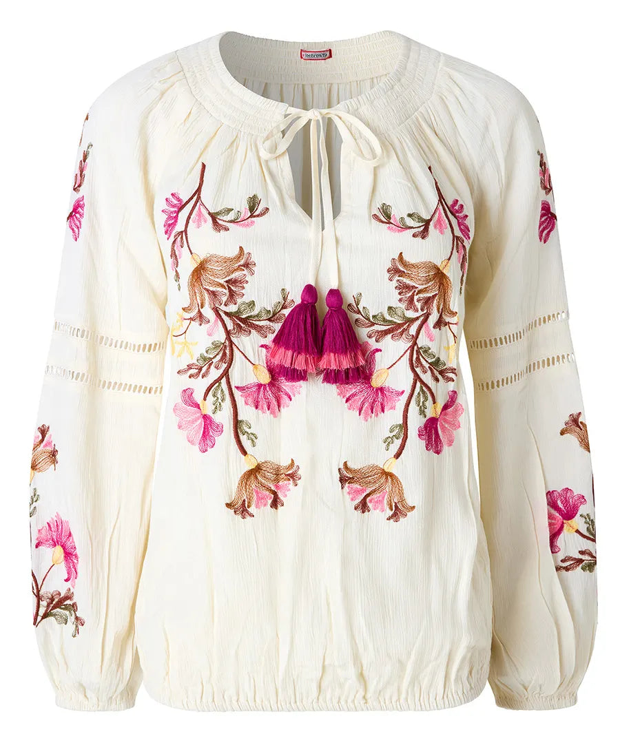 White blouse with floral embroidery and tassels on a white background