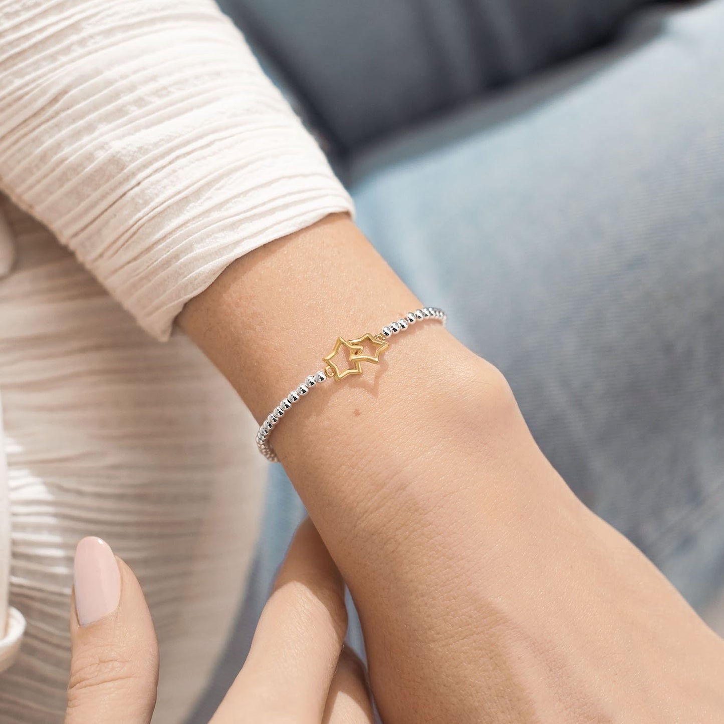 Close-up of a wrist wearing a delicate bracelet with a star charm.