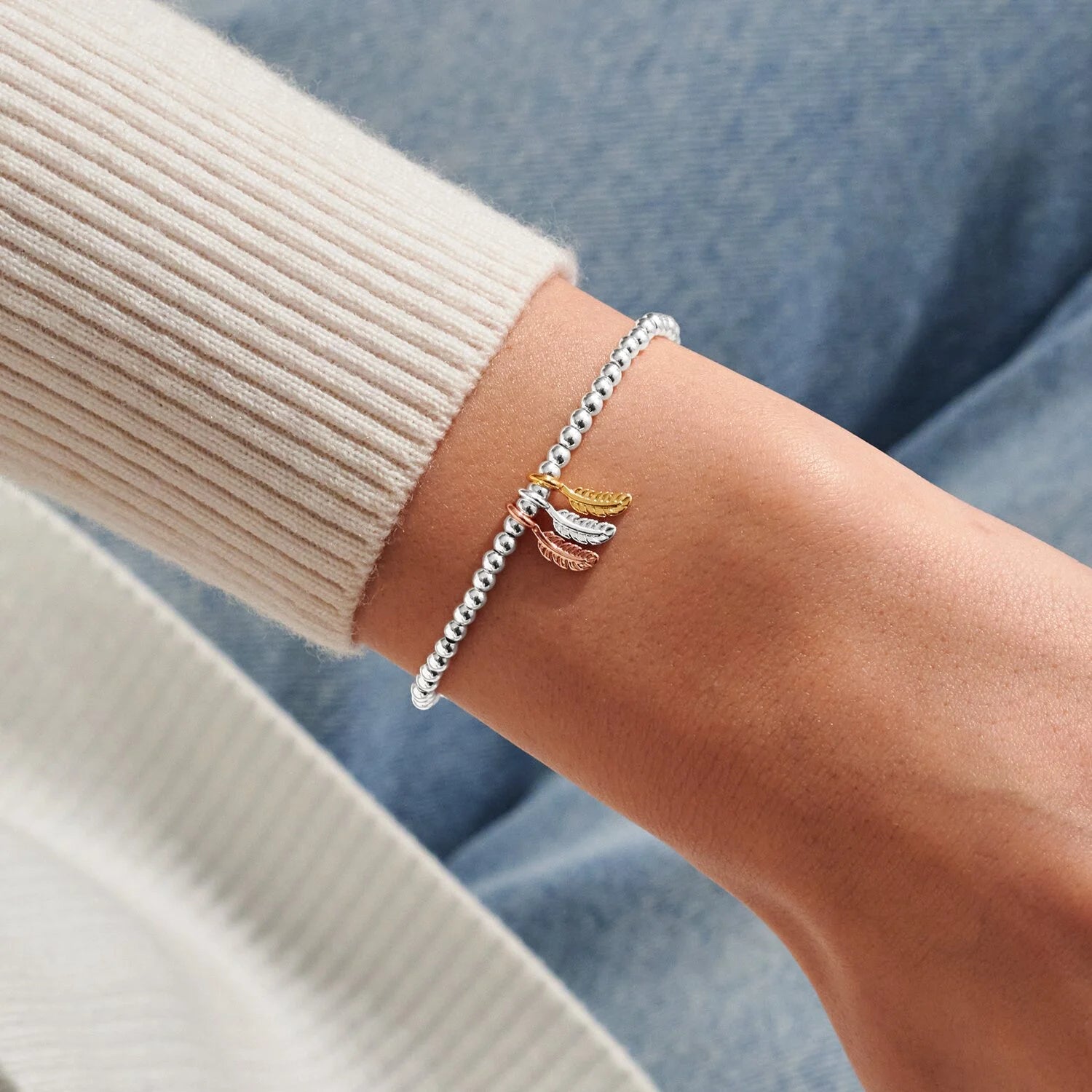 Close-up of a wrist wearing a silver bracelet with a small decorative element, against a blurred background.