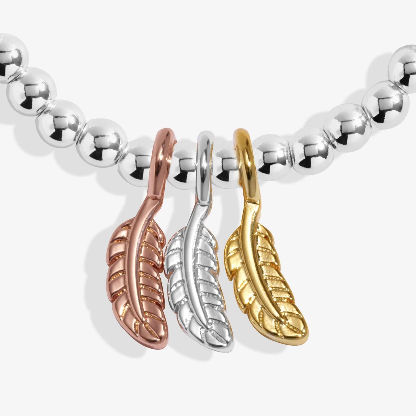 Bracelet with three feather-shaped charms in rose gold, silver, and gold on a white background.