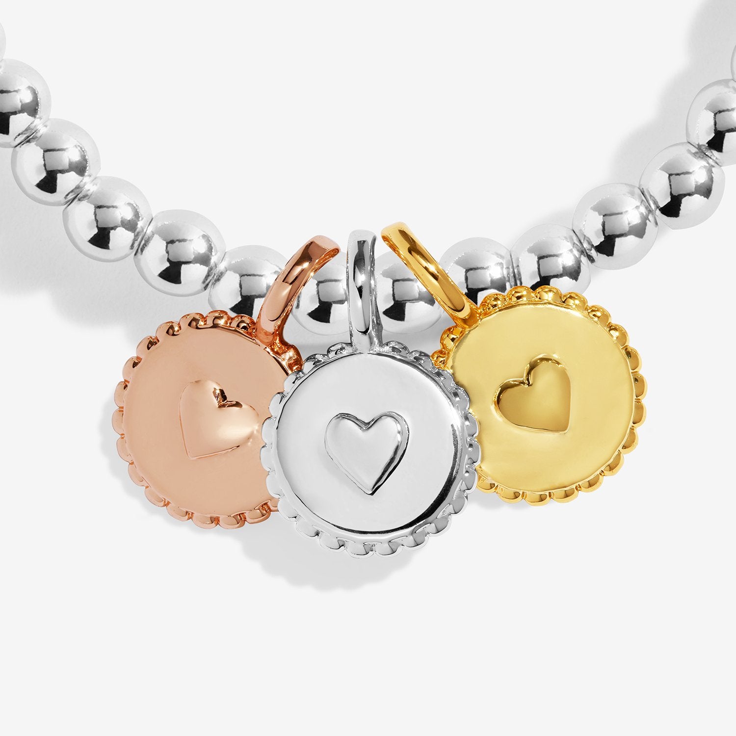 Bracelet with heart-shaped charms in silver, rose gold, and gold on a white background