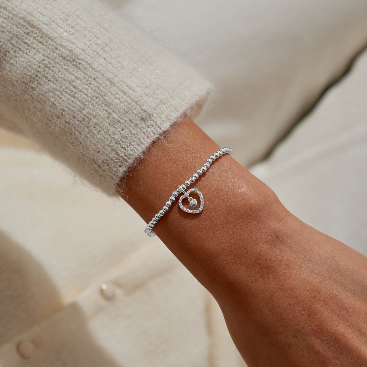 Silver bracelet on a wrist with a neutral background
