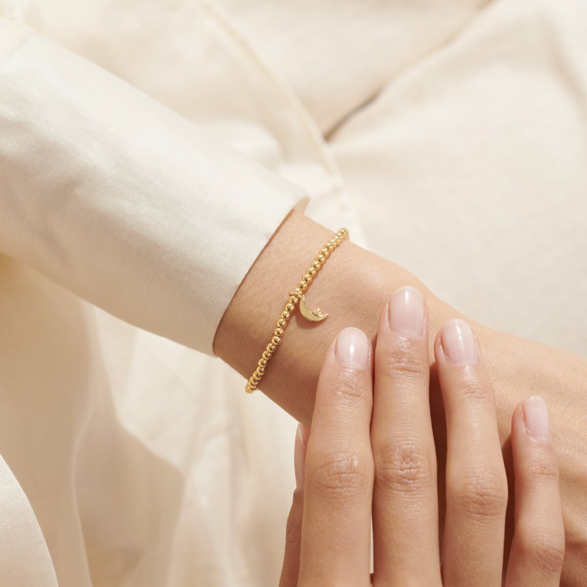 Gold bracelet on a wrist with a soft beige background