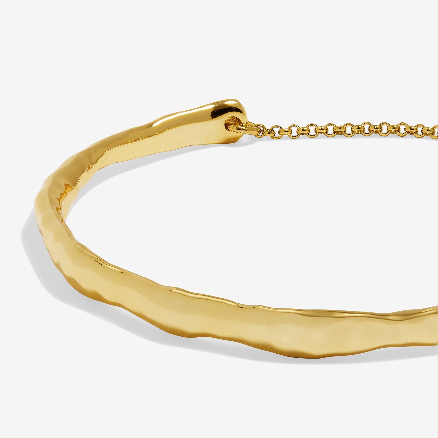 A close-up of a gold bangle bracelet with a hammered, organic textured finish and a matching gold chain extender, shown on a light gray background.