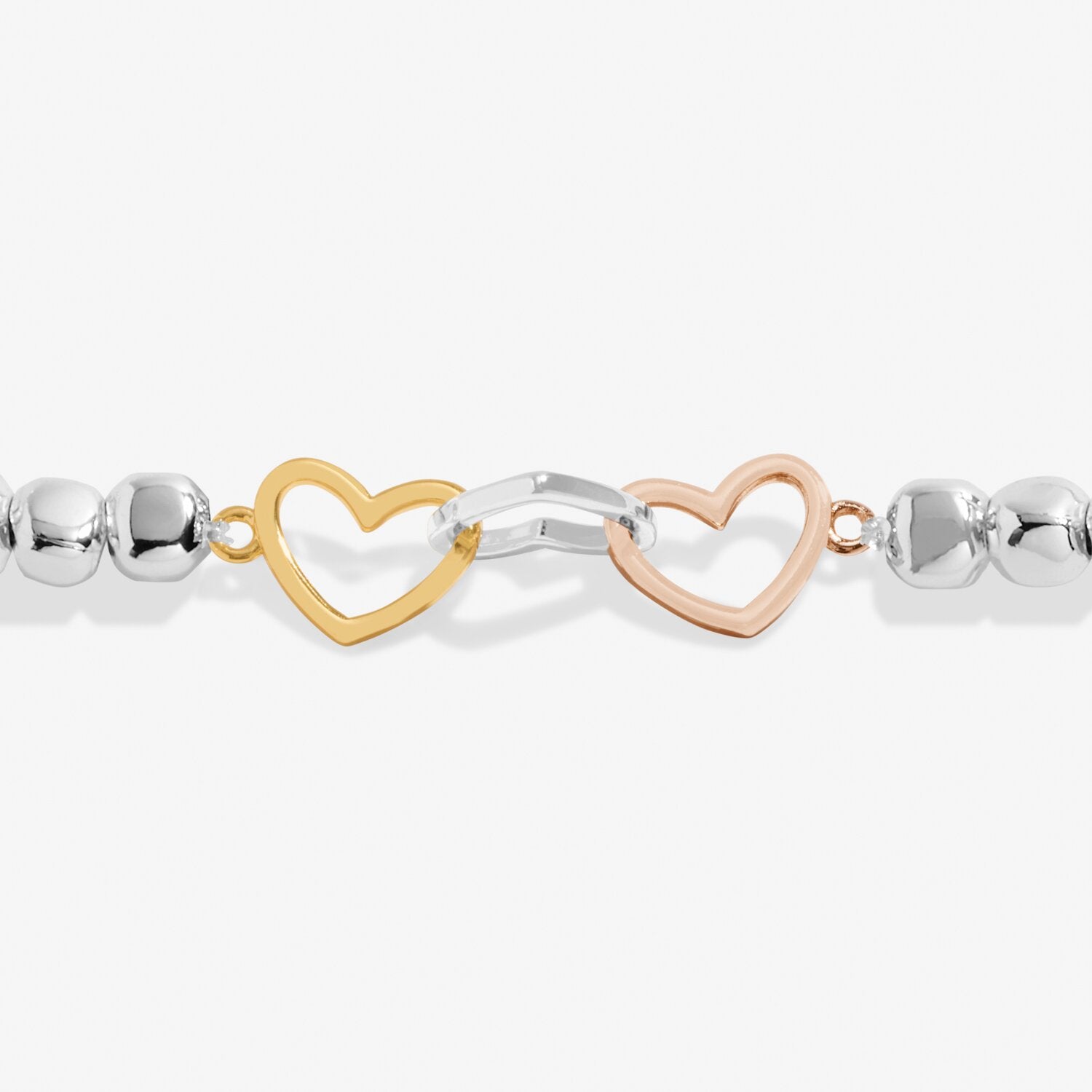 Bracelet with heart and infinity links in gold, silver, and rose gold on a white background