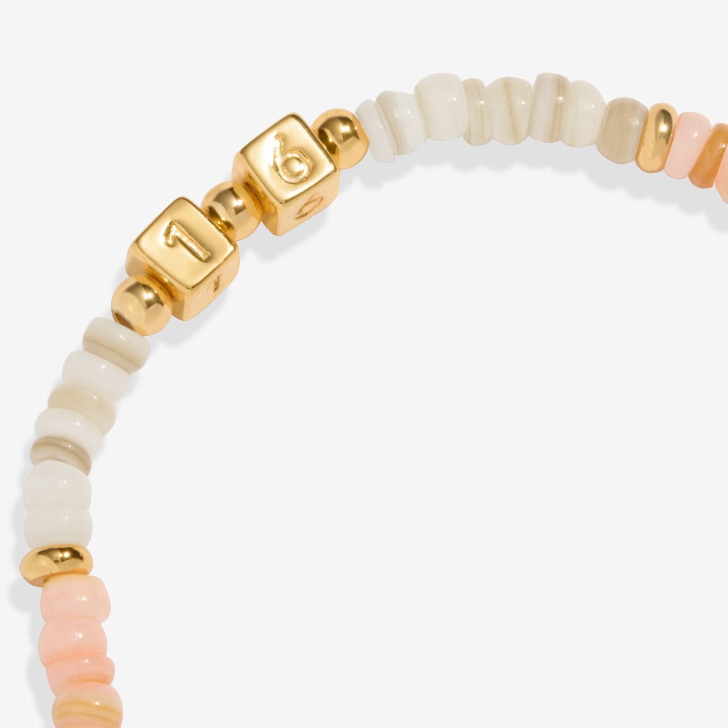 Bracelet with gold and pink beads on a white background