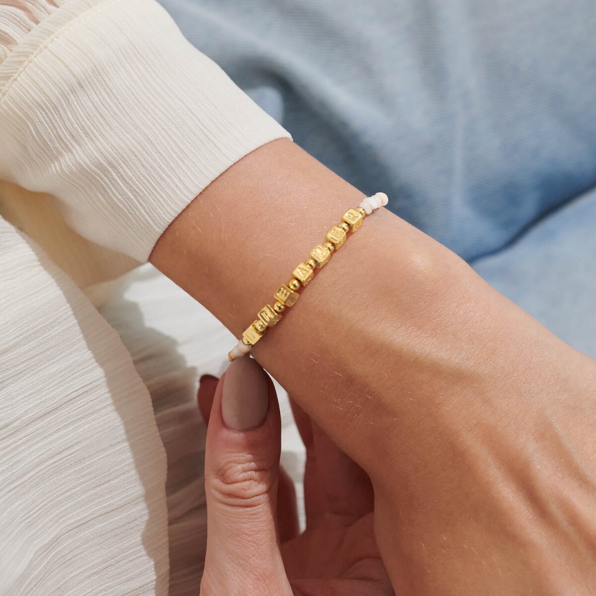 Gold beaded bracelet on a wrist with a blurred background