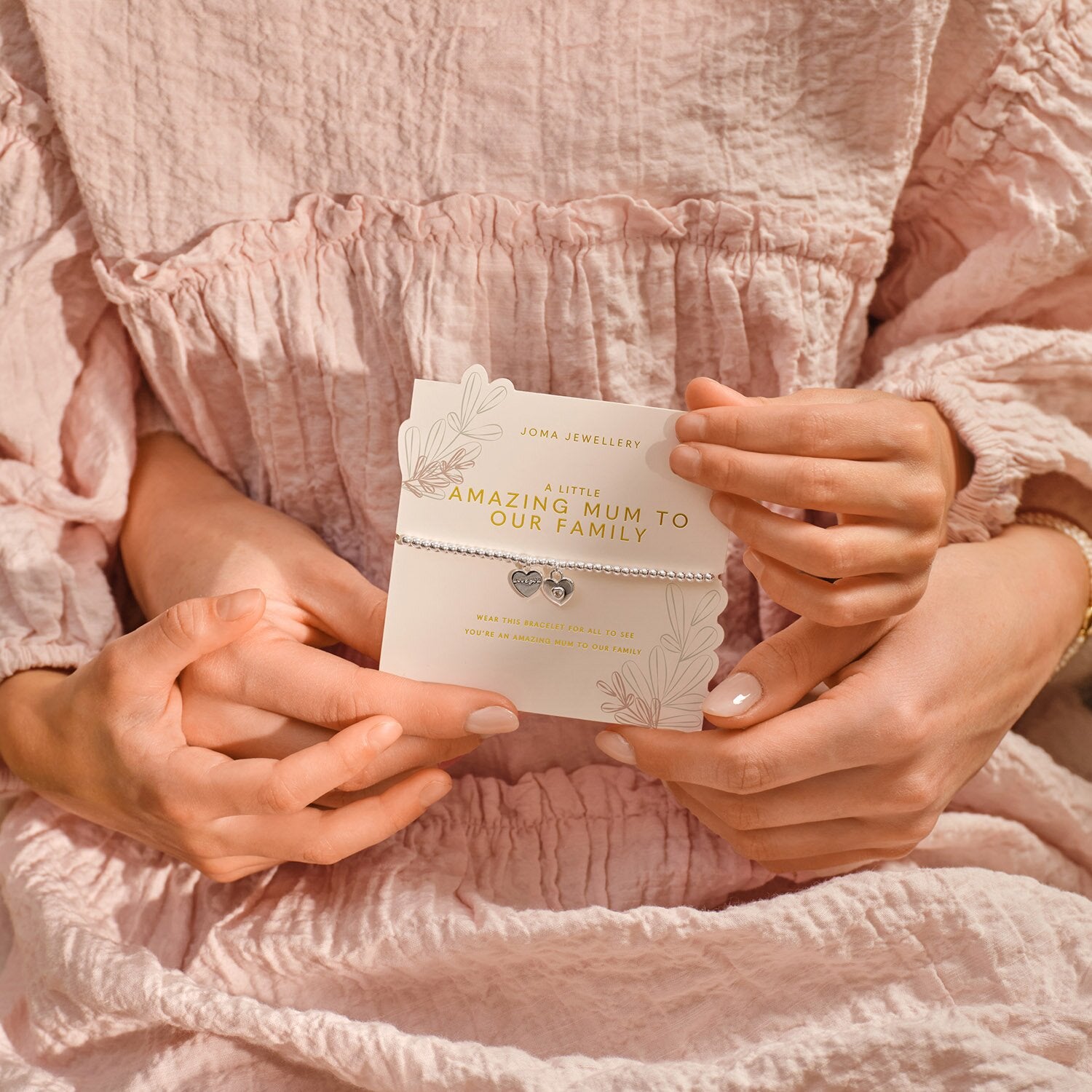 Person holding a card with text in a pink textured fabric setting