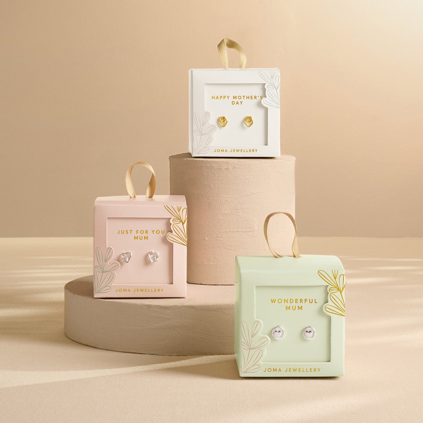Joma Jewellery earrings in decorative boxes on a beige background