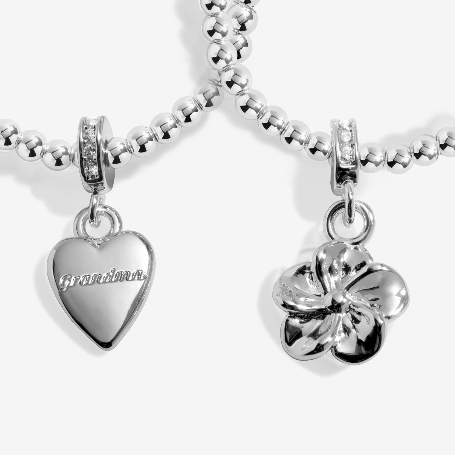 Silver charm bracelet with 'Grandma' heart charm and clover charm on a white background