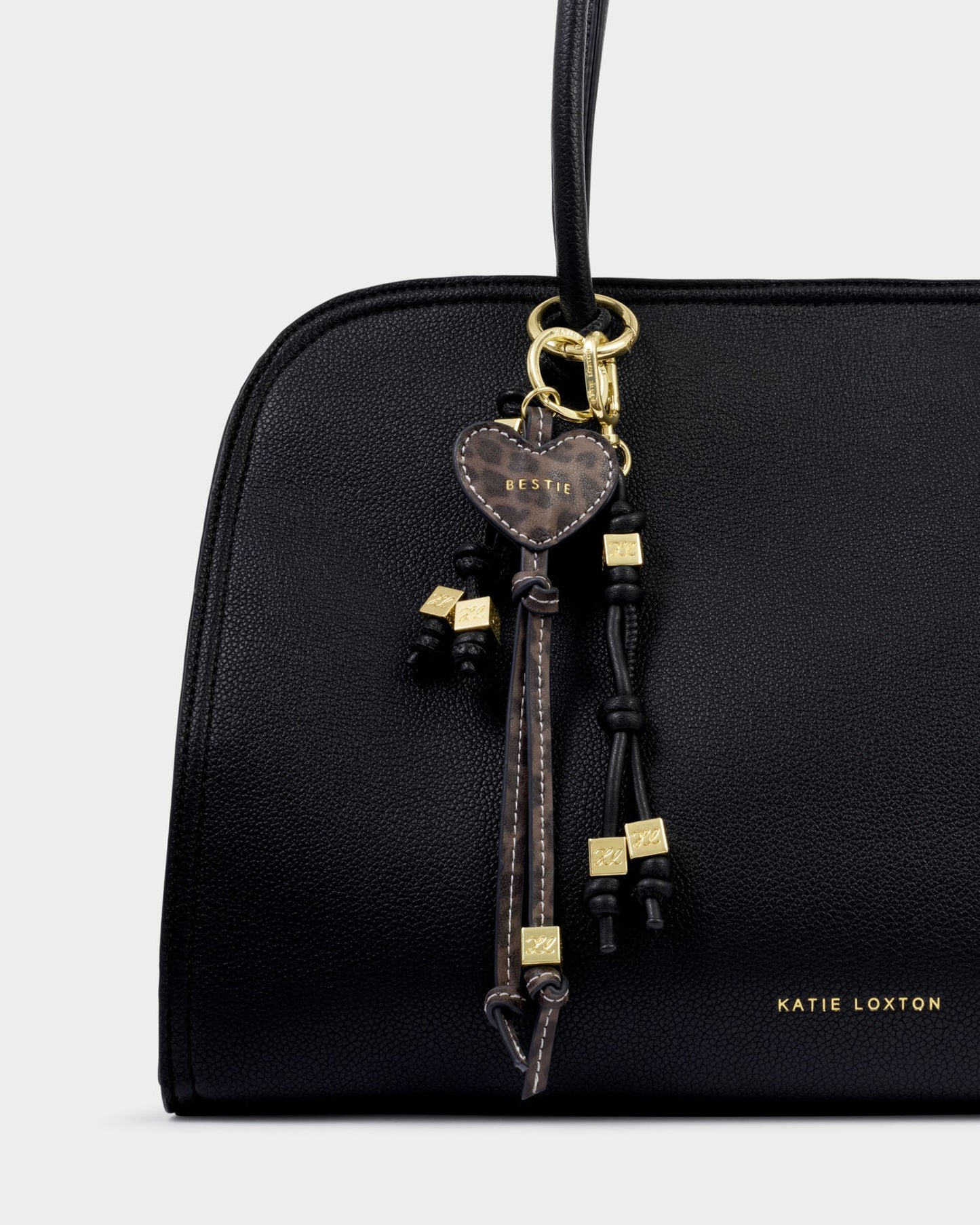 Black handbag with decorative keychain on a light gray background