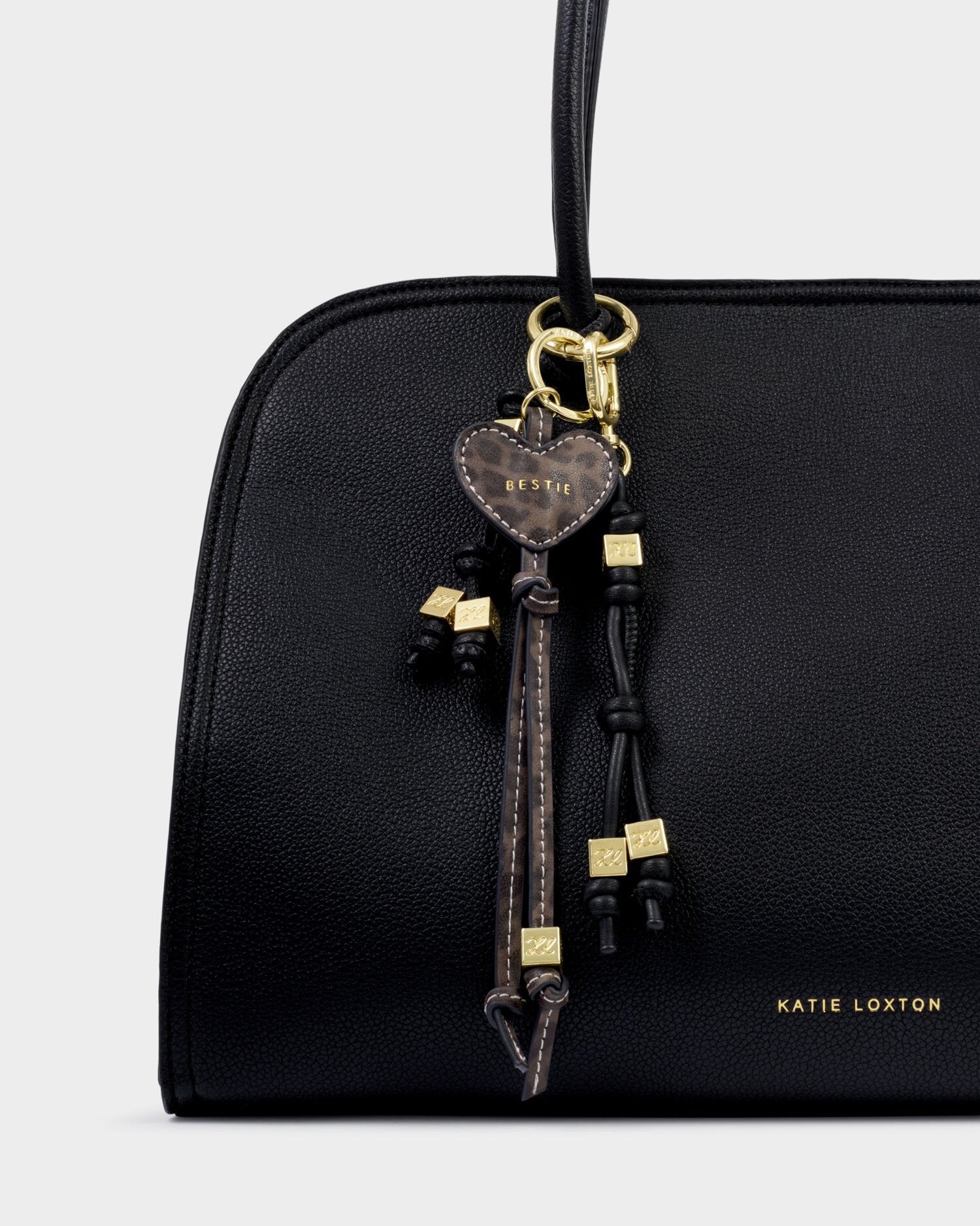 Black handbag with decorative keychain on a light gray background