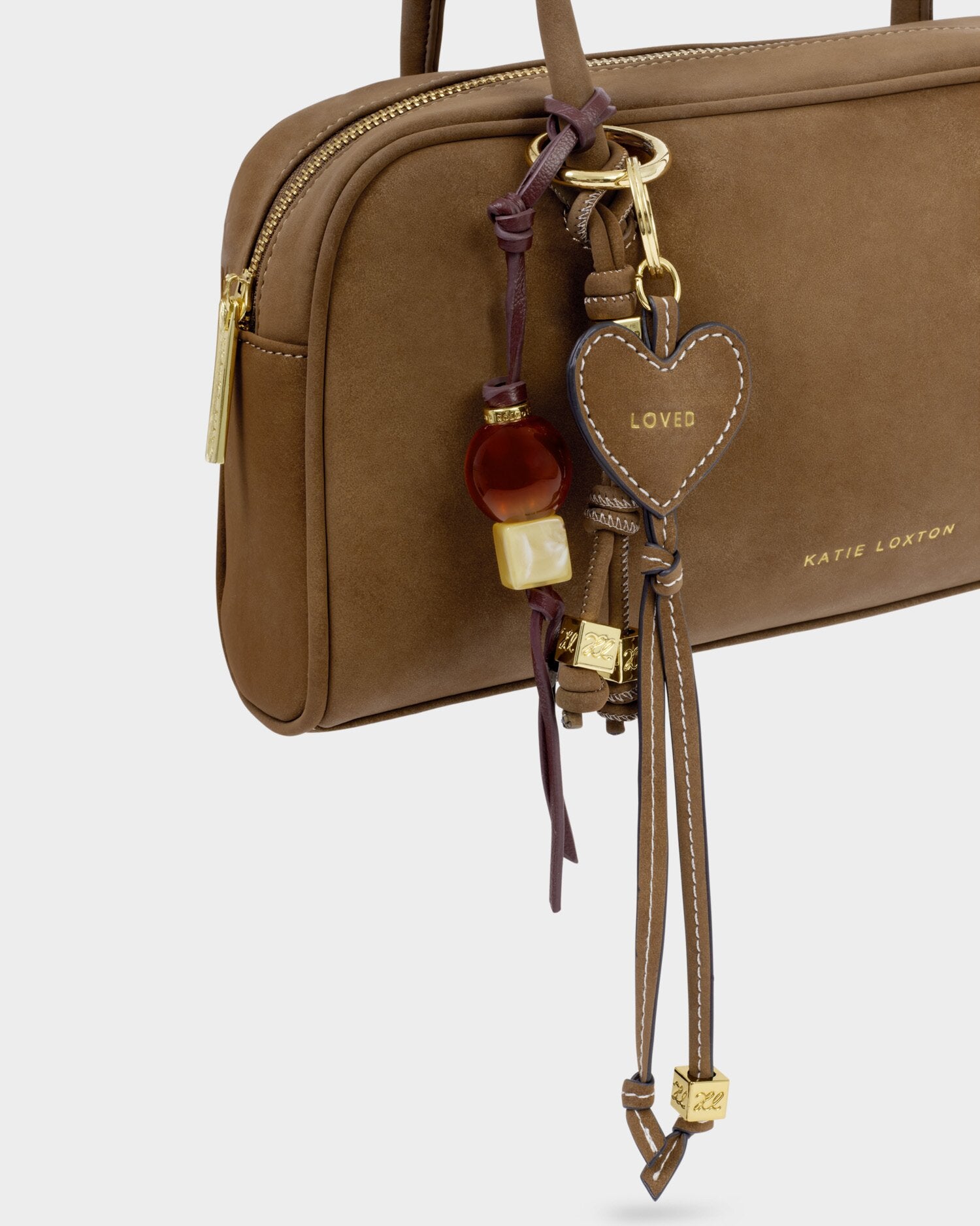 Brown handbag with decorative heart-shaped keychain on a light gray background