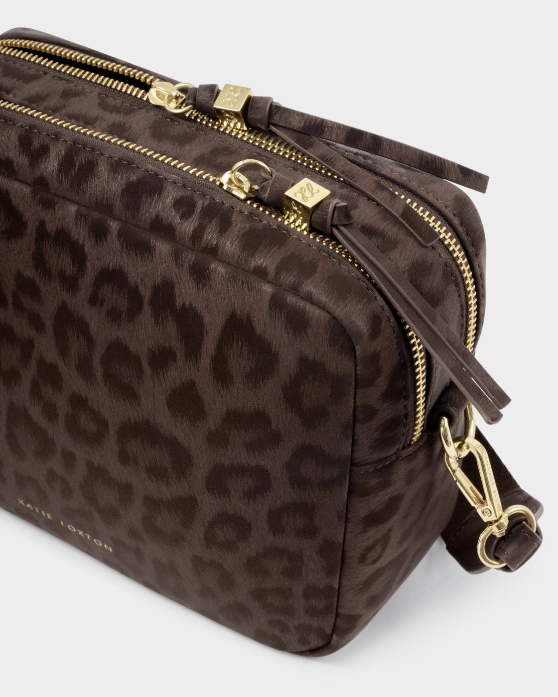 A close-up of a dark brown leopard-print crossbody bag with gold-tone hardware and a matching leather strap on a light gray background.