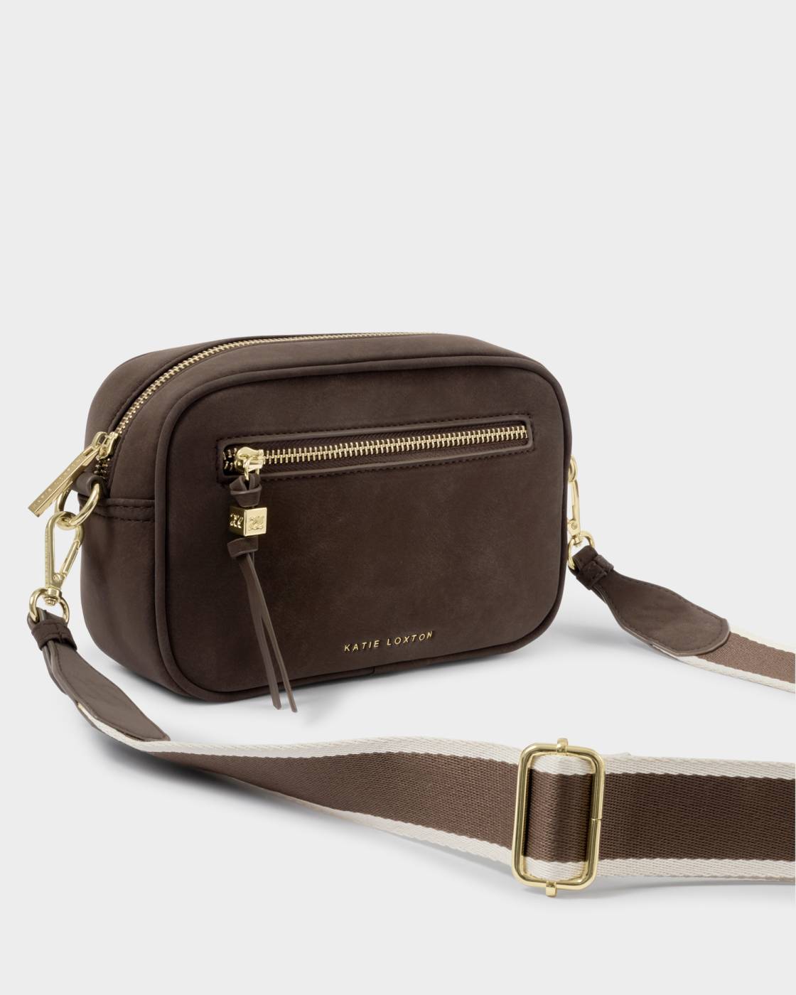 A dark brown crossbody camera bag with gold-tone hardware and a wide brown and white striped webbing strap, shown on a light gray background.