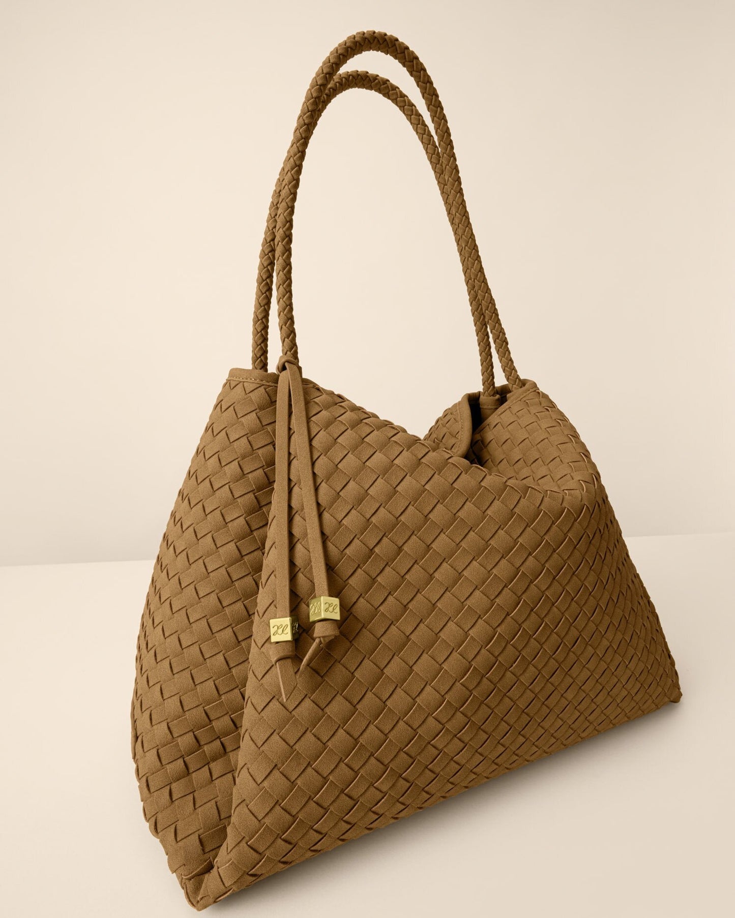Brown woven handbag with rope handles on a beige background
