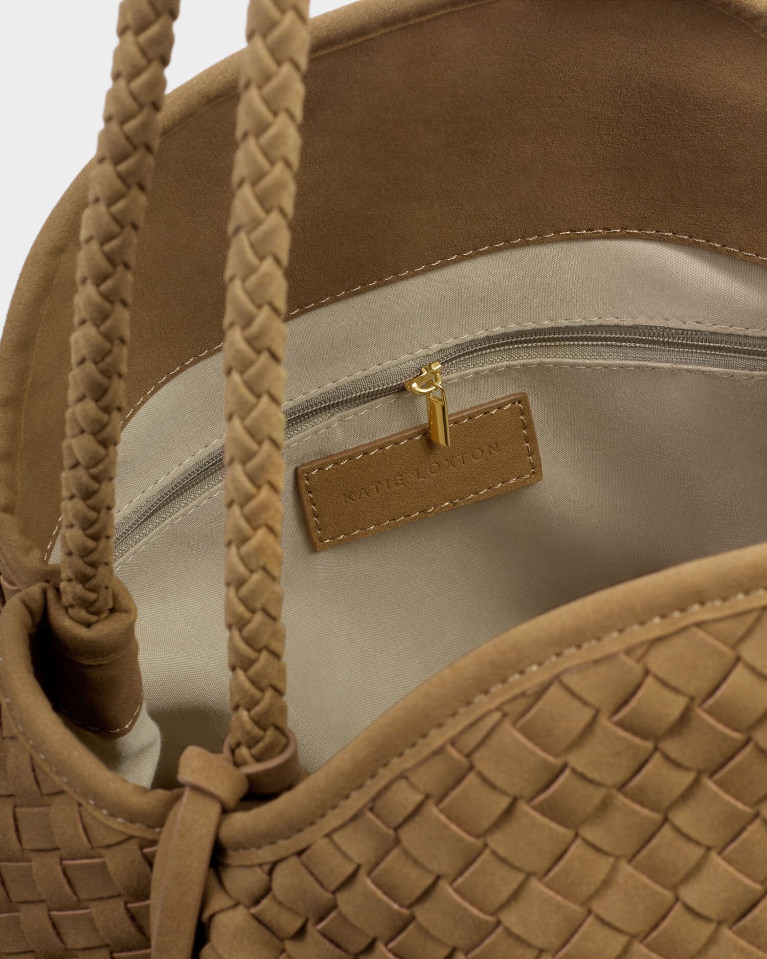 Close-up of a brown handbag with braided handles and visible brand logo.