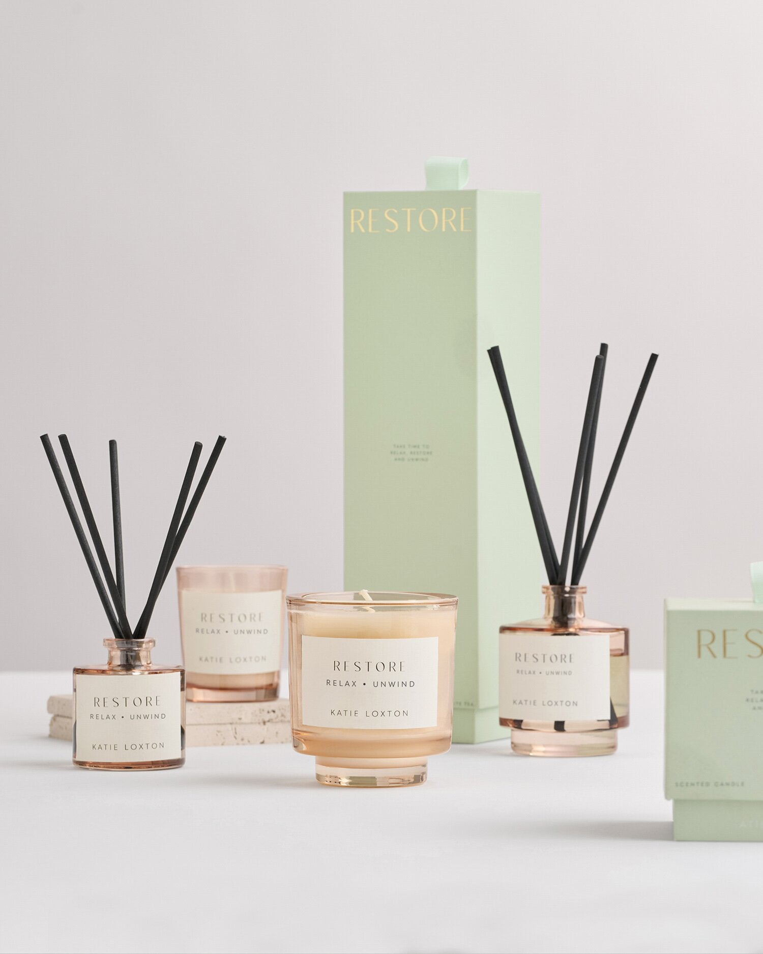 Set of 'Restore' candles and diffusers with packaging on a light gray background