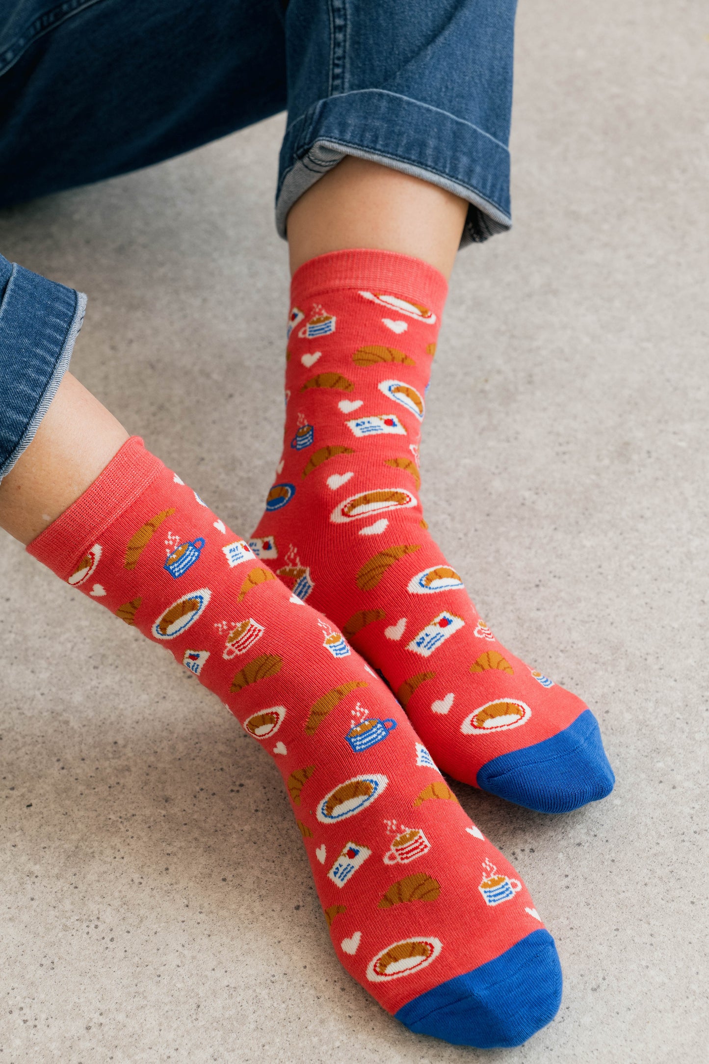 Red socks with colorful patterns worn by a person on a light gray floor.