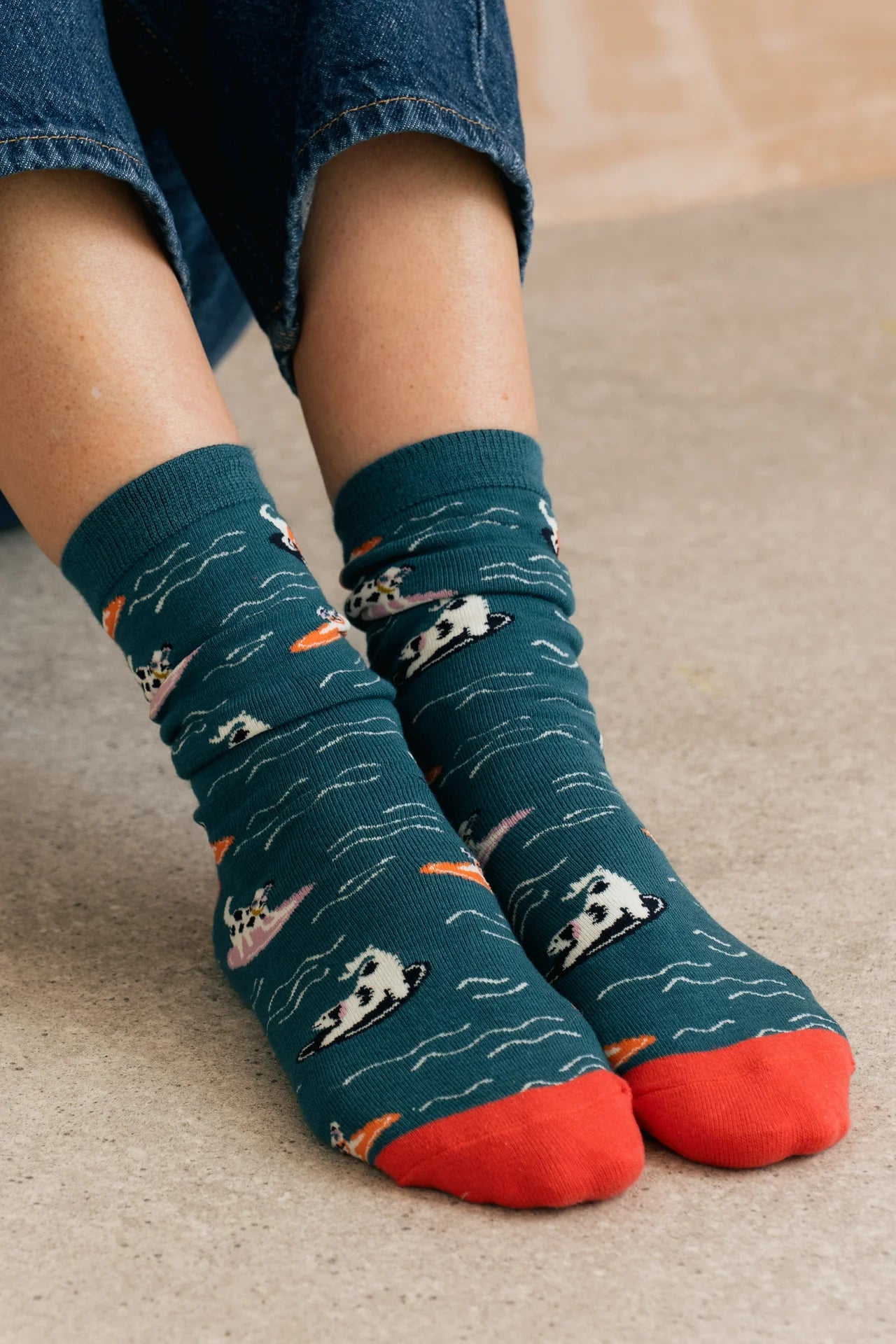 Person wearing blue socks with dog patterns and red toes on a beige carpet.