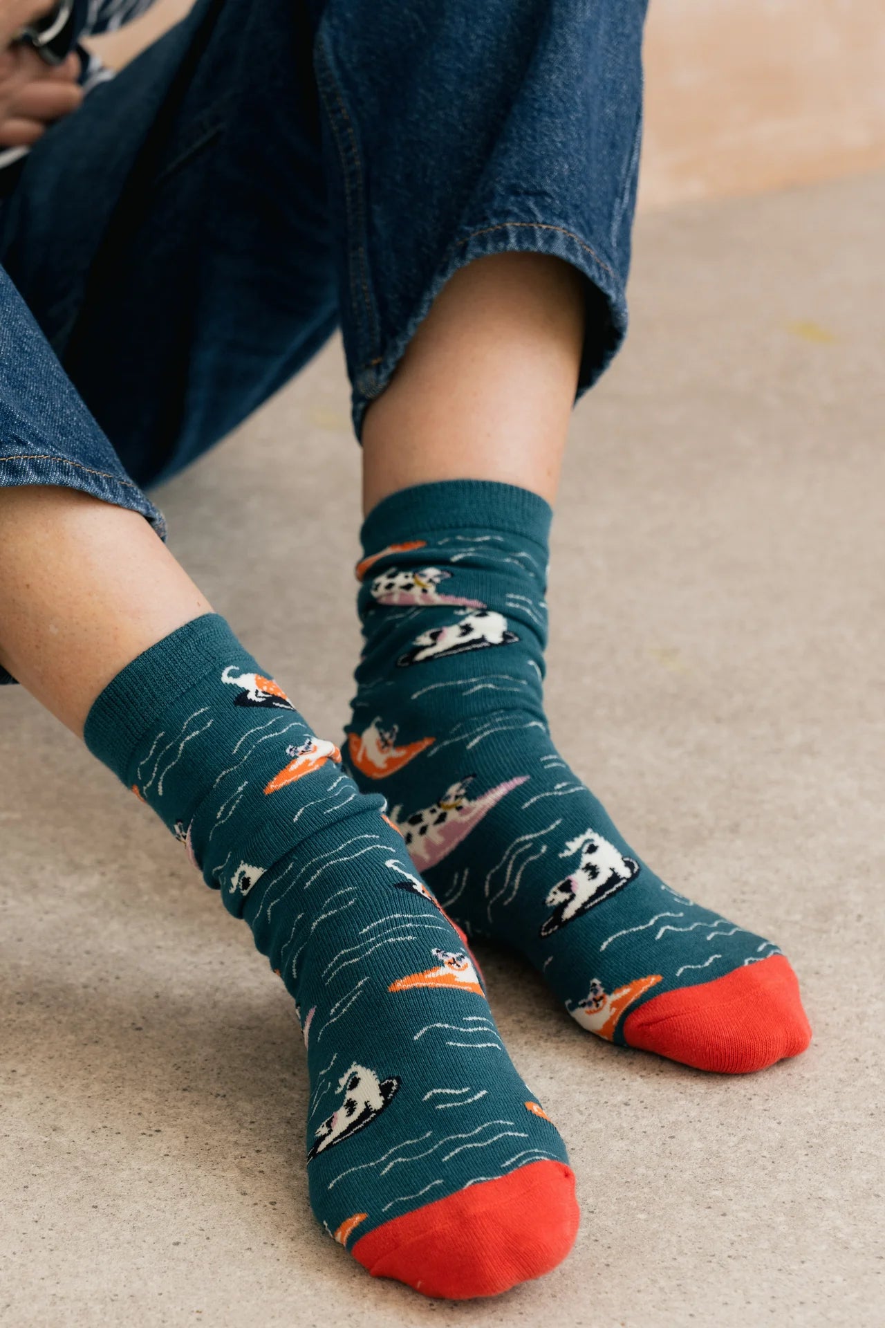 Person wearing blue socks with animal patterns on a beige carpet