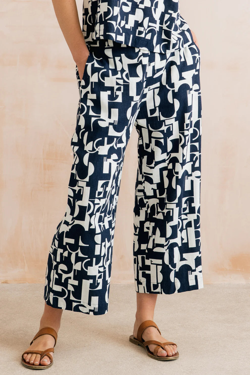 Person wearing navy and white patterned pants on a beige background