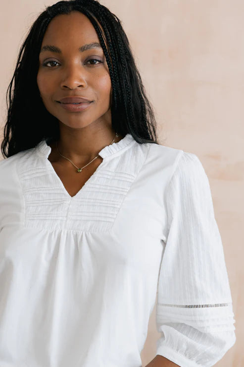 Woman wearing a white blouse against a beige background