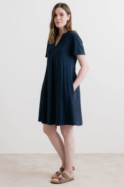 Woman wearing a navy blue dress with short sleeves and a V-neckline on a white background