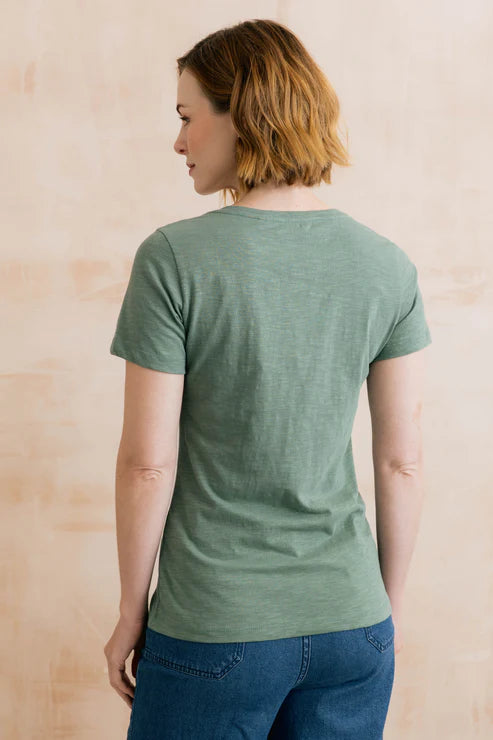 Person wearing a green t-shirt against a beige background