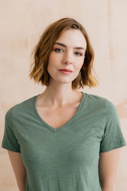 Woman wearing a green shirt against a beige background