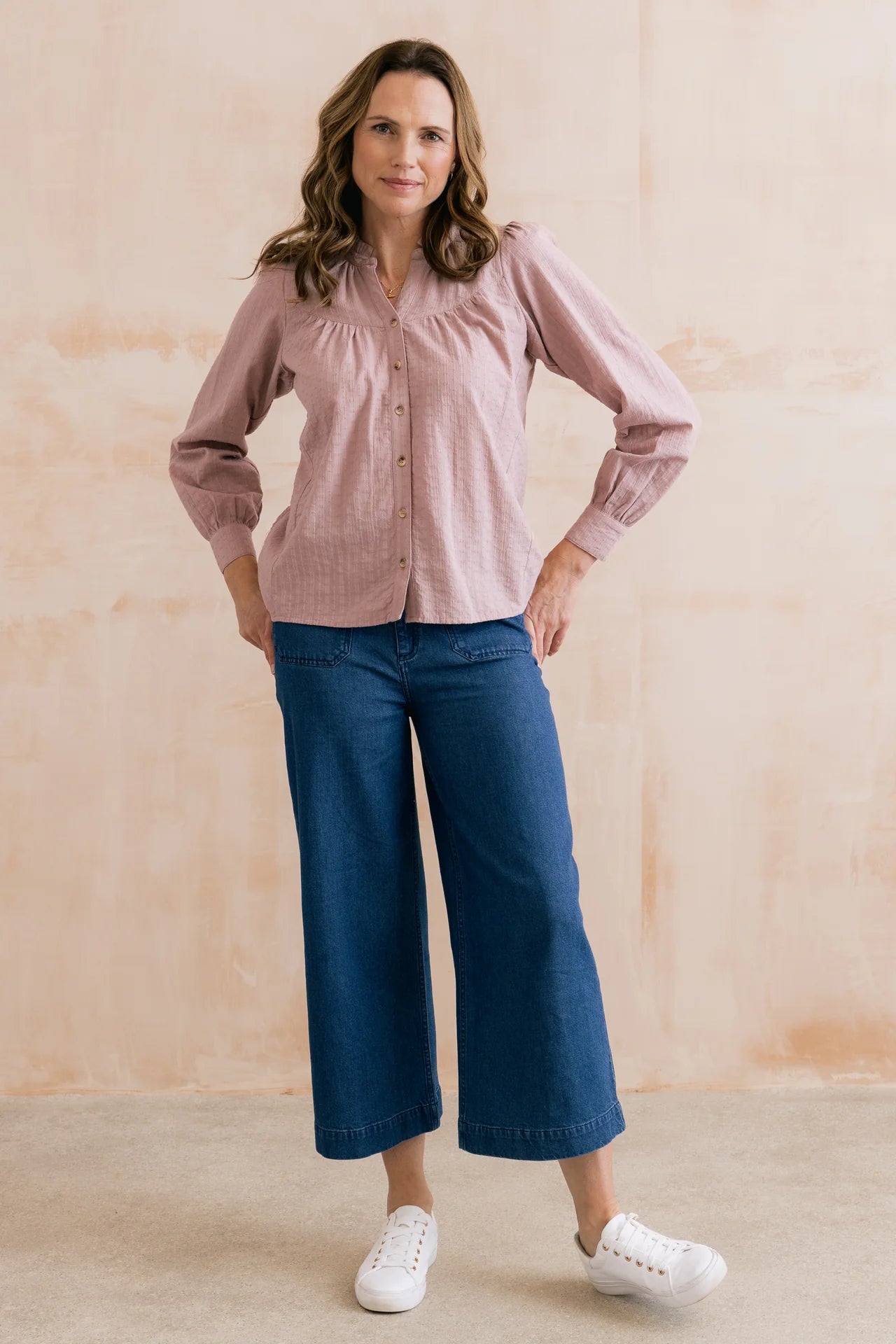 Women wearing soft pink blouse with jeans and white pumps