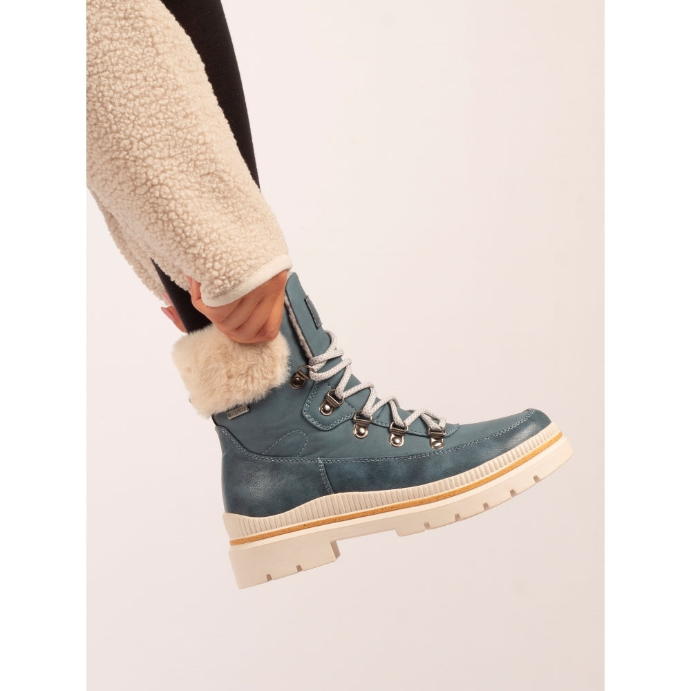 Blue winter boot with fur lining being worn on a light background