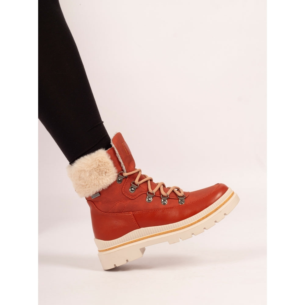 Orange winter boot with fur lining worn by a person on a white background