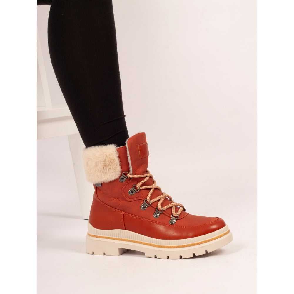 Orange winter boot with fur lining worn by a person on a white background