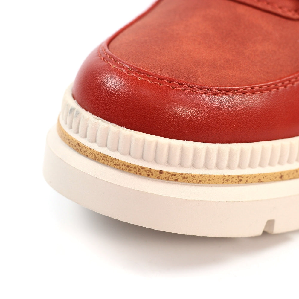 Close-up of a orange leather shoe with a white sole on a white background