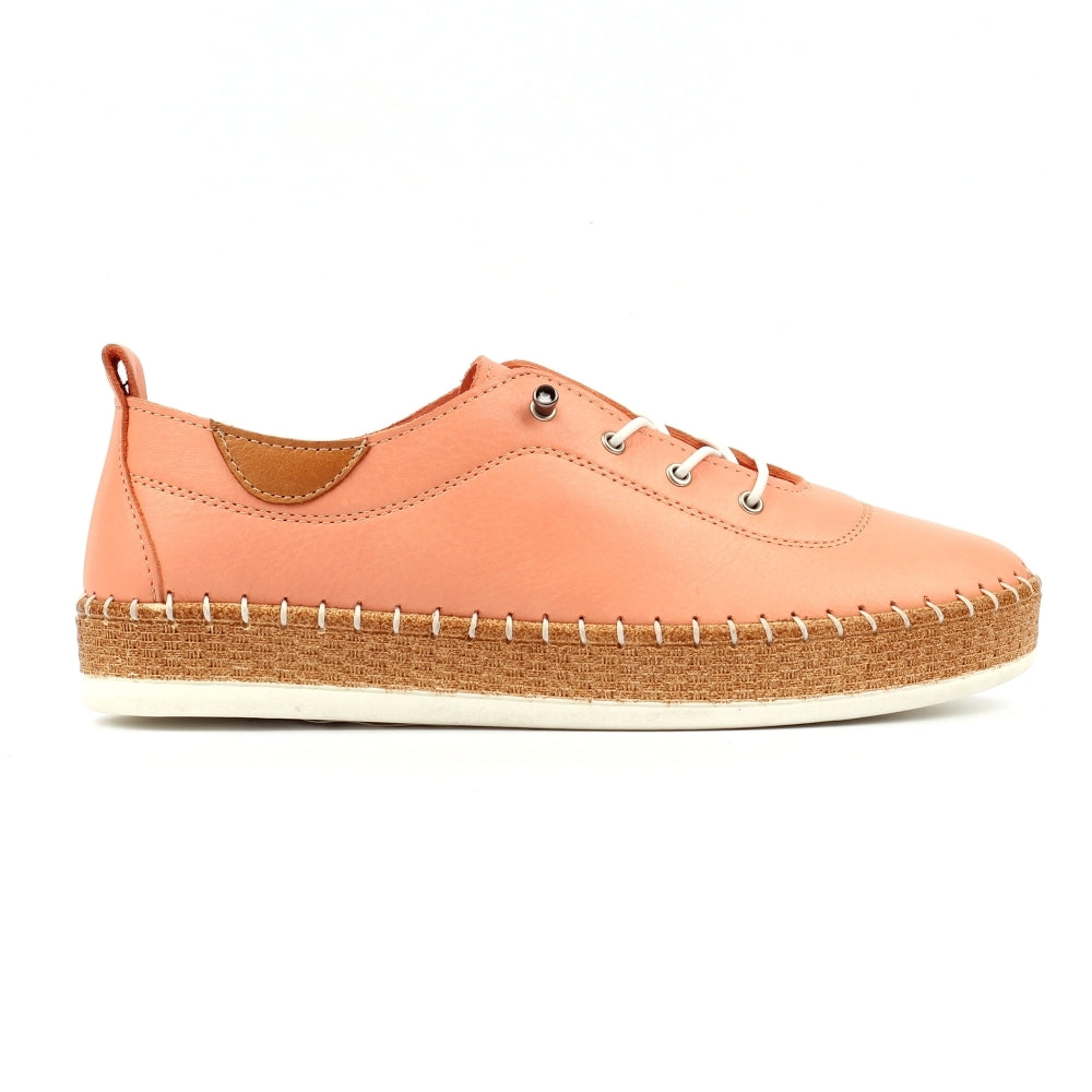 Peach-colored sneaker with a white sole on a white background