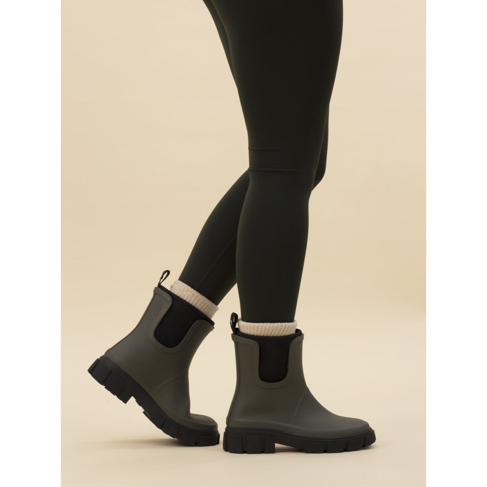 A person wearing black leggings and black olive wellington boots with elasticated side panels.