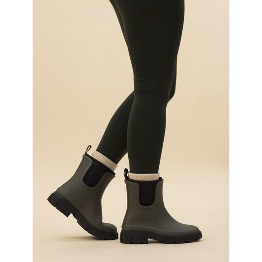 A person wearing black leggings and black olive wellington boots with elasticated side panels.