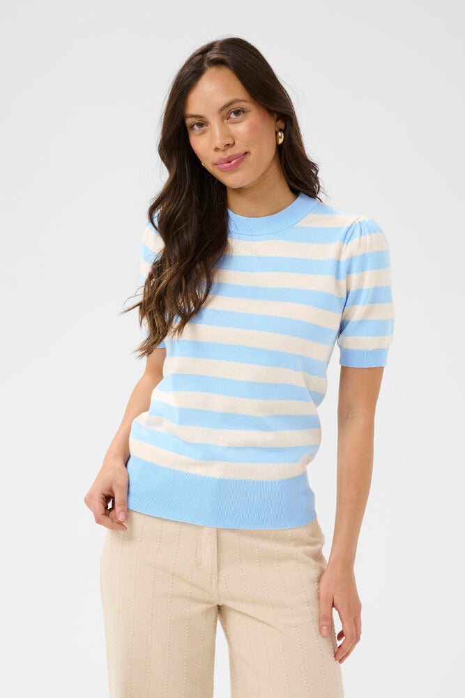 Woman wearing a light blue and beige striped sweater on a plain background