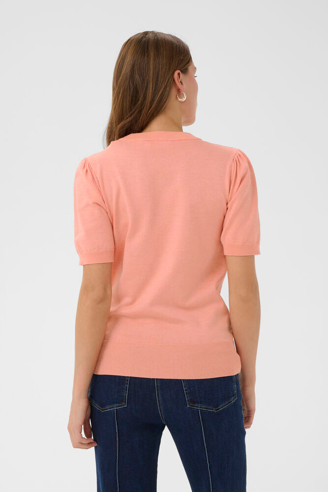 Woman wearing a pink top and blue jeans on a white background