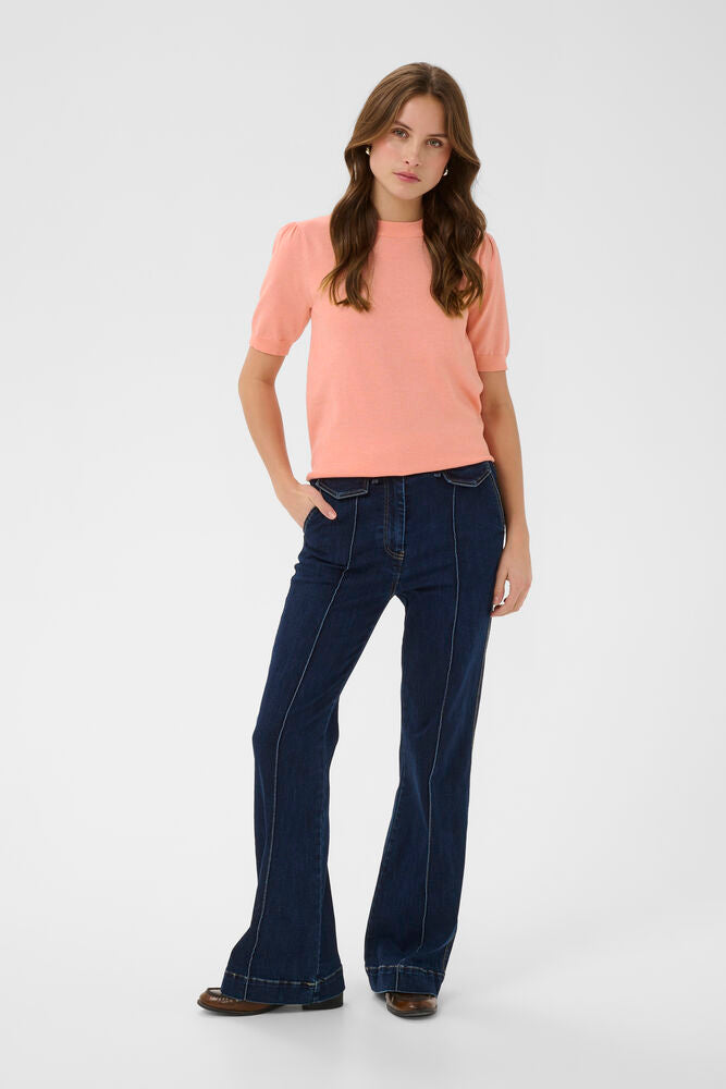 Woman wearing a pink top and blue jeans on a white background