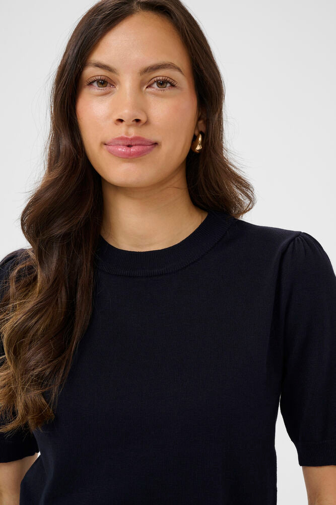 Woman wearing a Navy blue top against a white background