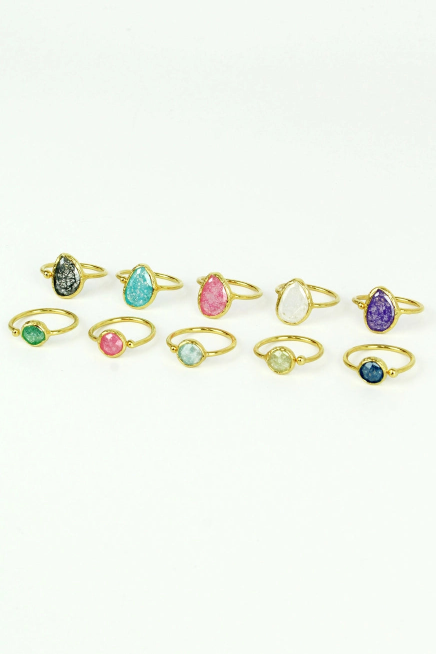Set of gold rings with multicolored gemstones on a white background