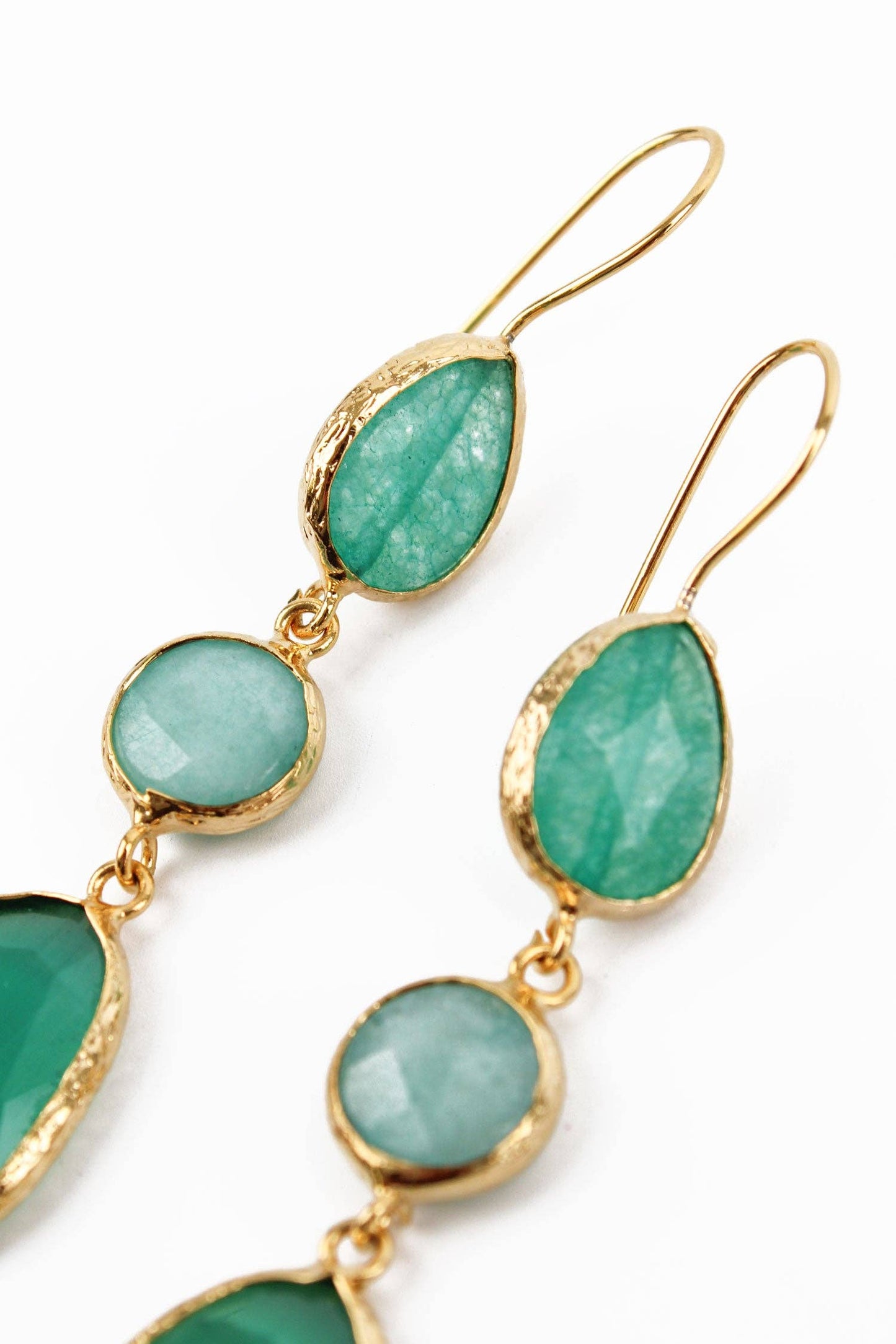 Gold earrings with green gemstones on a white background