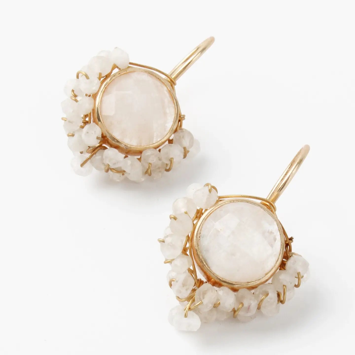 Pair of earrings with gold frames and white stones on a white background