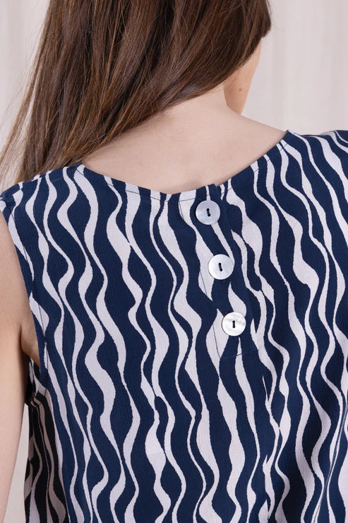 Navy and white patterned sleeveless top with buttons on a plain background