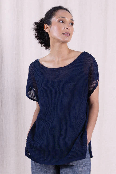 Woman wearing a navy blue knit top against a plain background