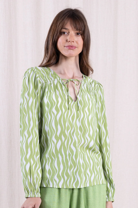 Woman wearing a green patterned blouse against a plain background