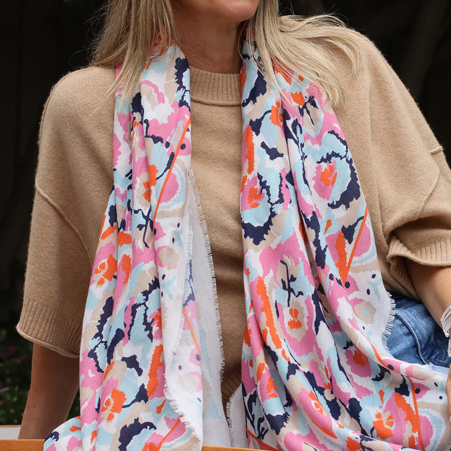 Person wearing a colorful patterned scarf with a neutral background